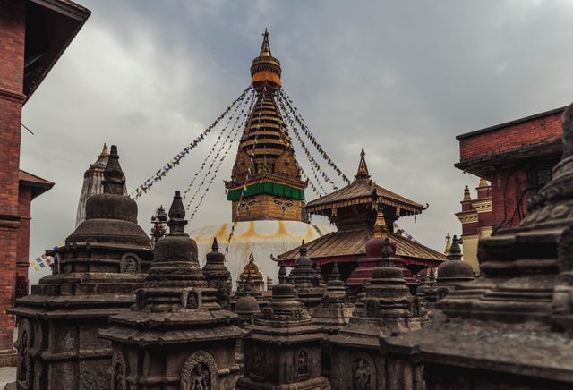 Prayer flags strung around Swayambhunath's golden stupa under a grey sky