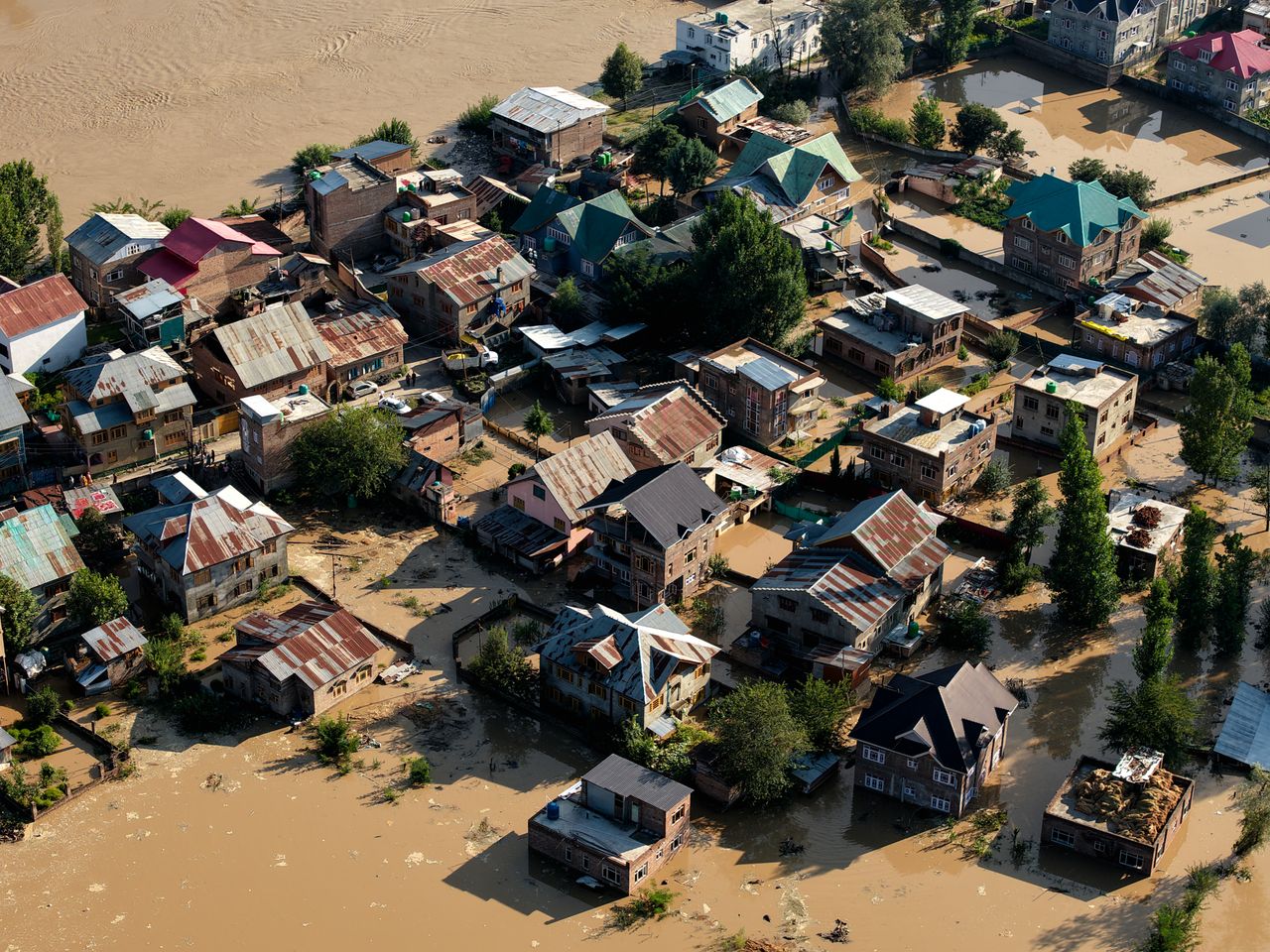 Aerial view of a flooded town, rooftops surrounded by muddy water