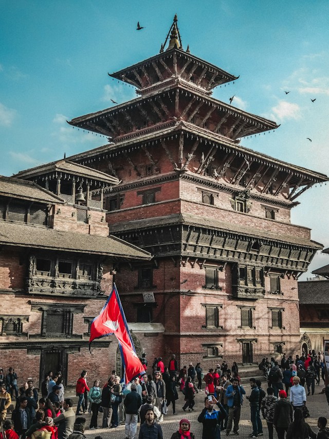 Crowds and prayer flags beneath a pagoda temple in a Kathmandu Valley durbar square